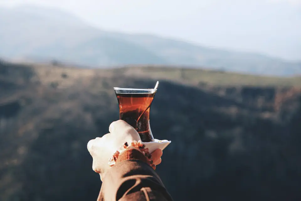 Yayla manzarasına karşı tutulan ince belli çay bardağı